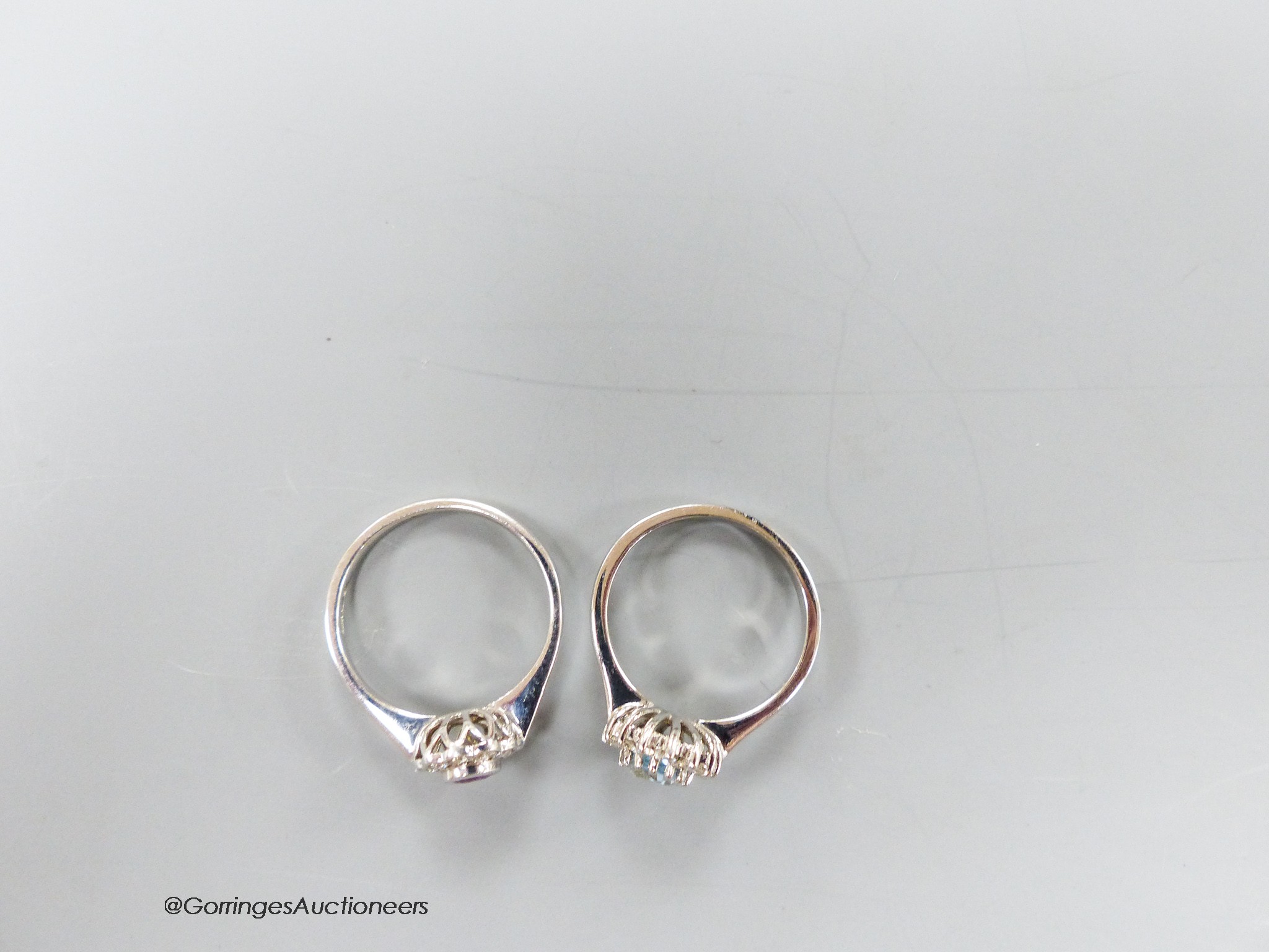 A modern 9ct white gold, pink sapphire and diamond cluster ring, size O and a similar blue topaz and diamond cluster ring, size N/O, gross 6.1 grams.